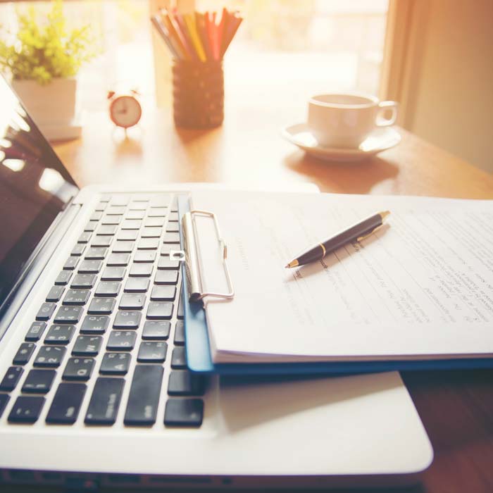 Contract and pen laying on a laptop keyboard